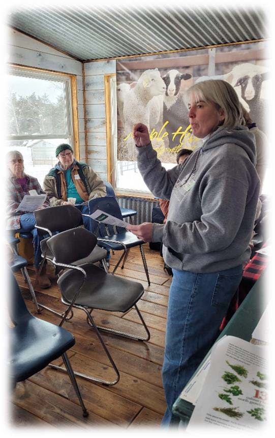 Woman stands in front of group of people explaining gardening