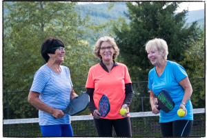 Three people holding pickle ball paddles