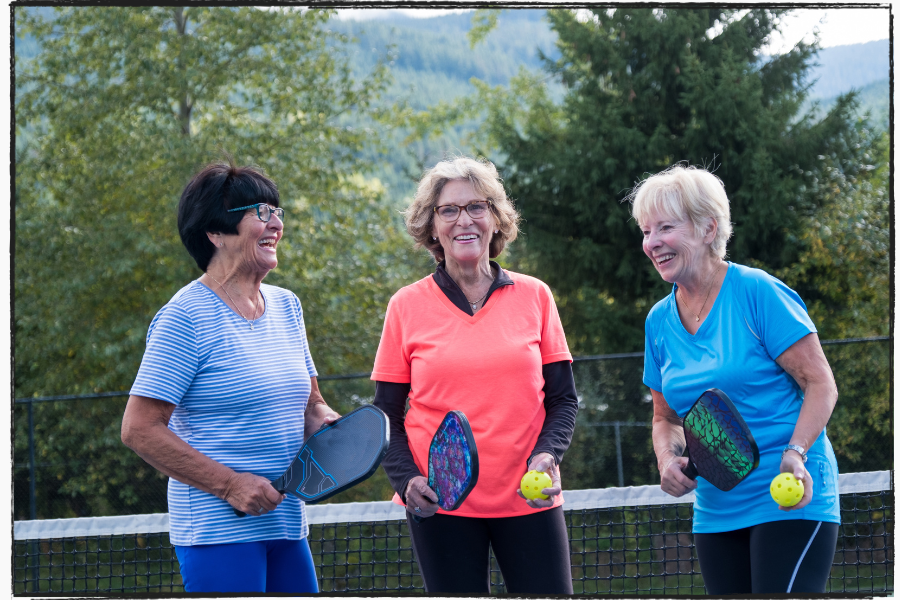 Three people holding pickle ball paddles