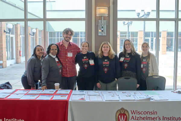 People wearing matching "Be one of 200" t-shirts stand behind a conference table