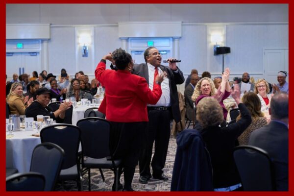 Two people stand and dance together in front of a conference ball room