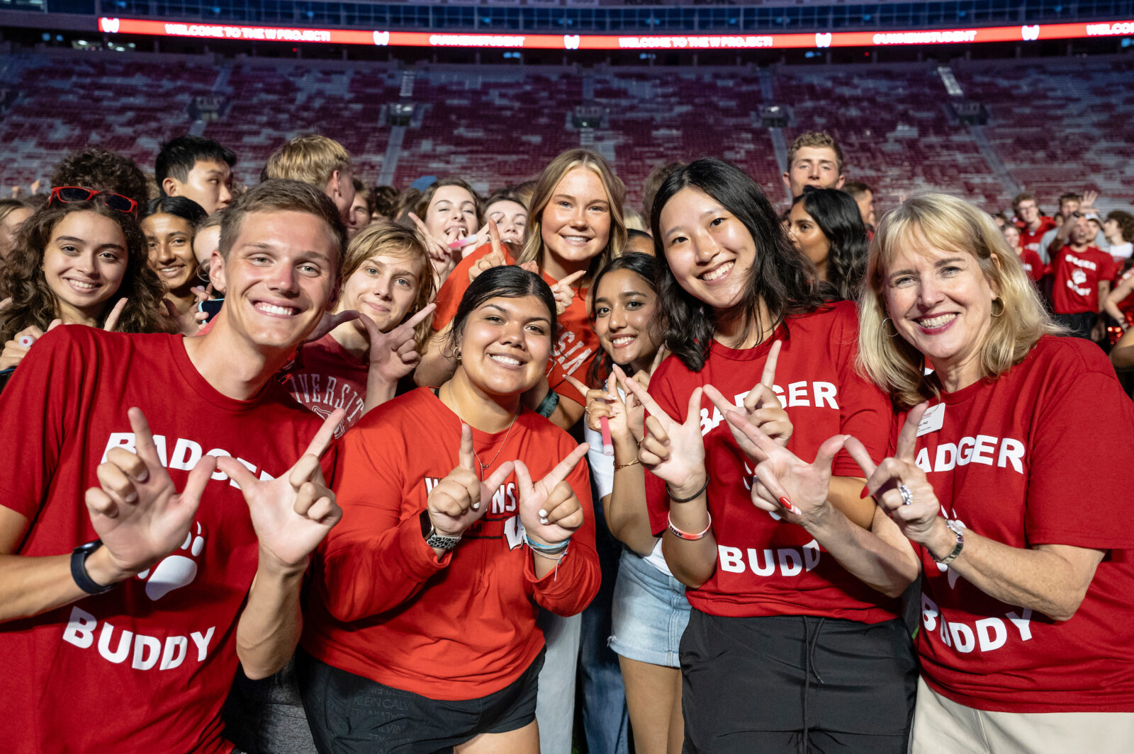 A group of UW students stand together and hold the "w" sign with their hands